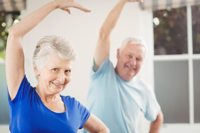 Portrait of senior couple performing stretching exercise at home.jpg